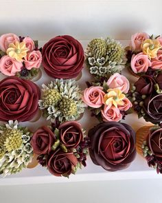 a box filled with lots of different colored flowers on top of a white table next to each other