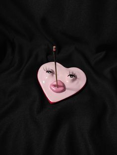 a pink heart shaped dish with eyelashes sticking out of it