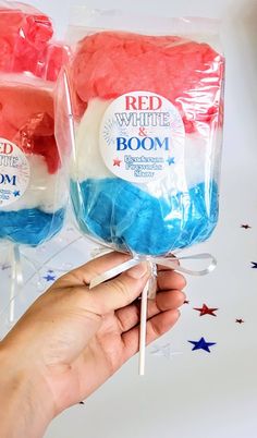 two red, white and blue lollipops are being held by someone's hand