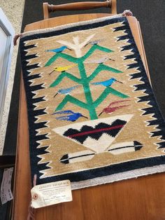 an old native american rug on display in a museum exhibit area with a wooden chair next to it