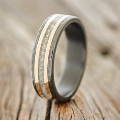 a wedding ring with antler wood and gold inlays on the inside is sitting on a piece of wood