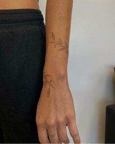 a woman's hand with a small tattoo on her left wrist and the other arm behind her