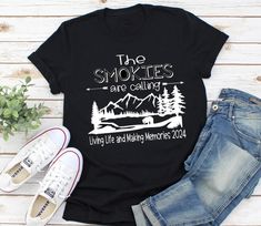 "Smoky Mountain Tee, Family Vacation Shirts, Mountain T-Shirt, Family Shirts, Mountain Vacation This listing is for mountain vacation t-shirts. This tee makes for great wear for the whole family!!  This design will be created on a soft unisex fit short sleeve t-shirt. See sizes and color options in the pictures above. SMOKIES CAN BE CHANGED TO ANY MOUNTAIN NAME or simply The Mountains are calling...   \"Living Life and Making Memories\" can be changed to Smith Family Vacation 2023 as well.  TODDLER MATCHING SIZES ARE ONLY AVAILABLE IN BLACK, HEATHER CHARCOAL, AND LIGHT HEATHER GRAY SHIPPING TIME: Tees are typically shipped out within 2-3 days.  **Custom orders and colors available! :)  Just message me or click the Request an Order Link under the preview photo.  BACK OF TEE ADD ON:  Paste t Cabin Trip Tshirt Ideas, Family Mountain Vacation Shirts, Black Hiking T-shirt With Letter Print, Black Letter Print T-shirt For Hiking, Black T-shirt For Hiking With Letter Print, Camping Text Print Crew Neck T-shirt, Custom Print Crew Neck T-shirt For Camping, Crew Neck T-shirt With Text Print For Camping, Casual Camping T-shirt With Text Print