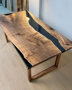 a table made out of wood and metal with black strips on the edge, sitting on a hard wood floor