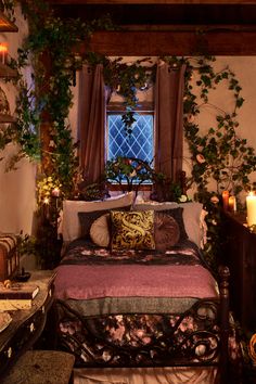 a bed sitting under a window covered in lots of greenery