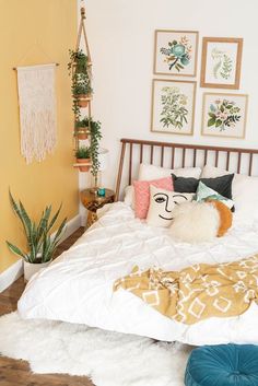 a bed with white sheets and pillows on top of it in a room filled with potted plants