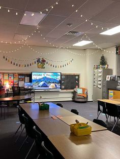 an empty classroom with desks and chairs in front of a television screen on the wall