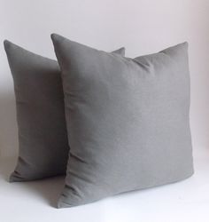 two gray pillows sitting next to each other