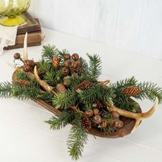 a wooden sleigh filled with pine cones and antlers sitting on top of a table