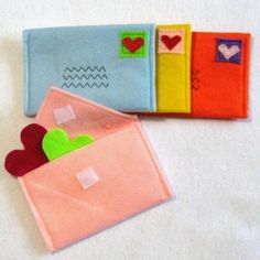 three felt envelopes with hearts on them sitting next to each other in the shape of an envelope