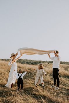 a group of people standing on top of a dry grass field holding a white scarf