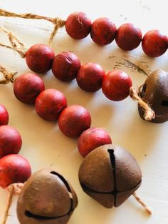 some red and brown beads are on a white surface with twine strings attached to them