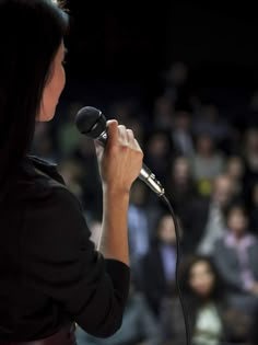 a woman holding a microphone in front of an audience