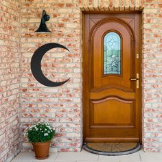 a wooden door with a crescent window and potted plant next to it on the side of a brick building