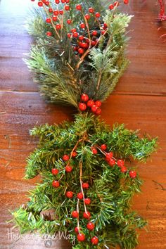 some red berries and green branches on a wooden table