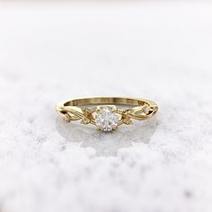 a yellow gold engagement ring with a single diamond in the center on a marble surface