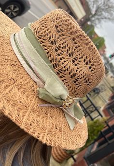 a woman wearing a straw hat with a green ribbon around the brimmed band