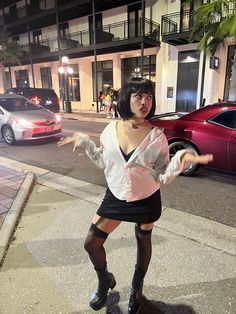 a woman dressed in black and white posing on the street with her arms spread out