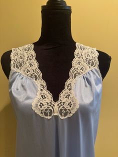 A elegant blue night gown with lace trim by Vanity Fair.  This vintage gown has beautiful lace work on the neckline and shoulder area.  Delicate lace trim on the armholes.  In good vintage condition  with no rips or stains.  The bust measures 18.5 inches from armpit to armpit laying flat.  52 inches from shoulder to hem.  Made in the USA.  Please examine the pics, feel free to ask questions. Lace Sleeveless Sleepwear For Pajama Party, Sleeveless Lace Sleepwear, V-neck Lace Trim Camisole For Pajama Party, Sleeveless Lace Nightgown For Pajama Party, Blue Sleeveless Camisole For Pajama Party, Blue V-neck Nightgown For Home, Blue Lace Sleeveless Sleepwear, Blue Sleeveless Lace Sleepwear, Blue V-neck Camisole For Daywear