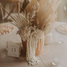 an arrangement of flowers in a vase on a table with a clock and napkins