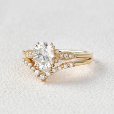 a close up of a ring with a diamond and pearls on the side, sitting on a white surface