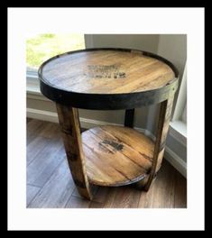 a round wooden table sitting on top of a hard wood floor next to a window