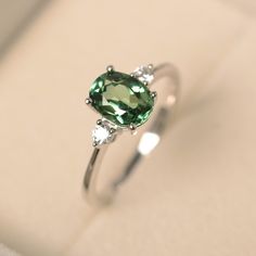 This ring features a (6*8 mm oval cut green sapphire). Customization is available. It is made by hand, and it will take about 7 days to finish the ring after your payment is completed. Main stone: 6*8mm oval cut Main stone weight:1.75ct Metal type: sterling silver finished with rhodium/14k gold Accent stone: cz Customization is available, I also can make it with 14k solid gold (white or yellow or rose) and diamond accent stone, just feel free to contact me. Any question, just let me know. :) My Green Diamond Ring Silver, Green Oval Ring, Green Stone Ring Silver, Silver Rings With Green Stones, Blue Green Sapphire Engagement Ring White Gold, Green Saffire Engagement Ring, Green Diamond Ring Engagement, Sapphire Green Engagement Ring, Silver Green Engagement Ring