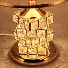 a table lamp that has been made out of gold colored glass cubes and is sitting on a marble surface