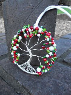 a tree brooch with red, green and white beads hanging from it's center