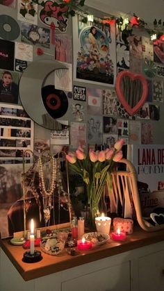 a table topped with lots of candles next to a wall covered in pictures and photos