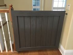 a wooden gate sitting in the middle of a room next to a stair case and window