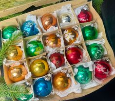 a box filled with lots of different colored christmas ornament ornaments on top of a table