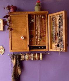 a wooden cabinet filled with lots of bracelets and necklaces hanging from it's sides