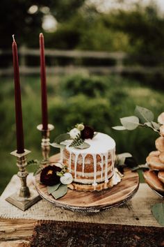 a cake sitting on top of a wooden table next to candles and other desserts