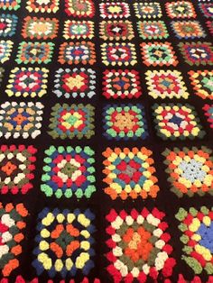 a crocheted blanket with many different colored squares on it, all arranged in the same pattern