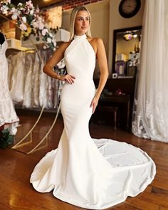 a woman in a white dress standing on a wooden floor with her hands on her hips