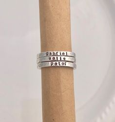 "STERLING SILVER NAME RINGS This listing features beautiful sterling silver rings that are hand stamped with your choice of name or saying as well as spacer ring options. This listing is for ONE ring. The pictures show multiple rings stacked to show the effect of the rings together. The rings are solid sterling silver. Each name ring measures just over 3mm wide. The bead spacer ring measures 2mm wide and the stardust spacer ring measures 1.5mm wide. The personalized rings will be hand stamped wi Adjustable Silver Rings With Meaningful Style, Adjustable Silver Meaningful Rings, Adjustable Sterling Silver Engraved Ring, Nickel Free, Meaningful Adjustable Silver Stackable Rings, Adjustable Personalized Silver Stackable Rings, Adjustable Sterling Silver Stackable Rings, Adjustable Nickel Free Sterling Silver Engraved Ring, Adjustable Nickel-free Sterling Silver Engraved Ring, Personalized Silver Ring With Meaningful Style