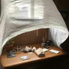 an open book sitting on top of a wooden table under a white sheet covered bed