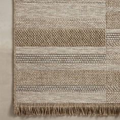 a beige rug with fringes on top of it