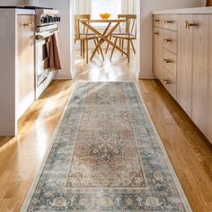 a large rug is in the middle of a kitchen with white cabinets and wooden floors