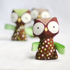 three little owl figurines sitting next to each other on a white tablecloth