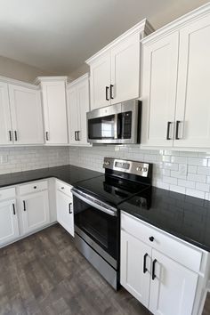 an empty kitchen with white cabinets and black counter tops is seen in this image from the front view