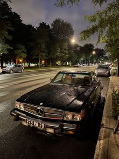 two cars parked on the side of the road in front of some trees at night