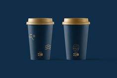 two coffee cups sitting side by side on a dark blue background with gold rims