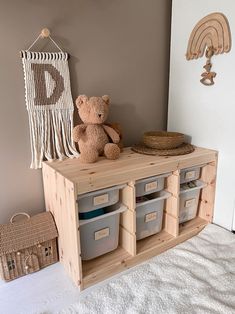 a teddy bear sitting on top of a wooden shelf next to bins and baskets