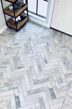 a white door and some shelves on the side of a brick floor in front of a window