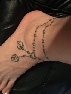 a woman's foot with a rosary tattoo on the side of her left leg