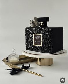 a black and white cake sitting on top of a table next to a bottle of perfume