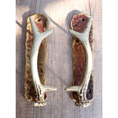 two deer antlers are sitting on top of a wooden table, one is white and the other is brown