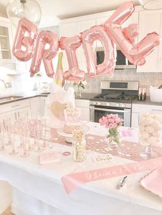 the table is set up with pink and gold balloons that spell out the word bride